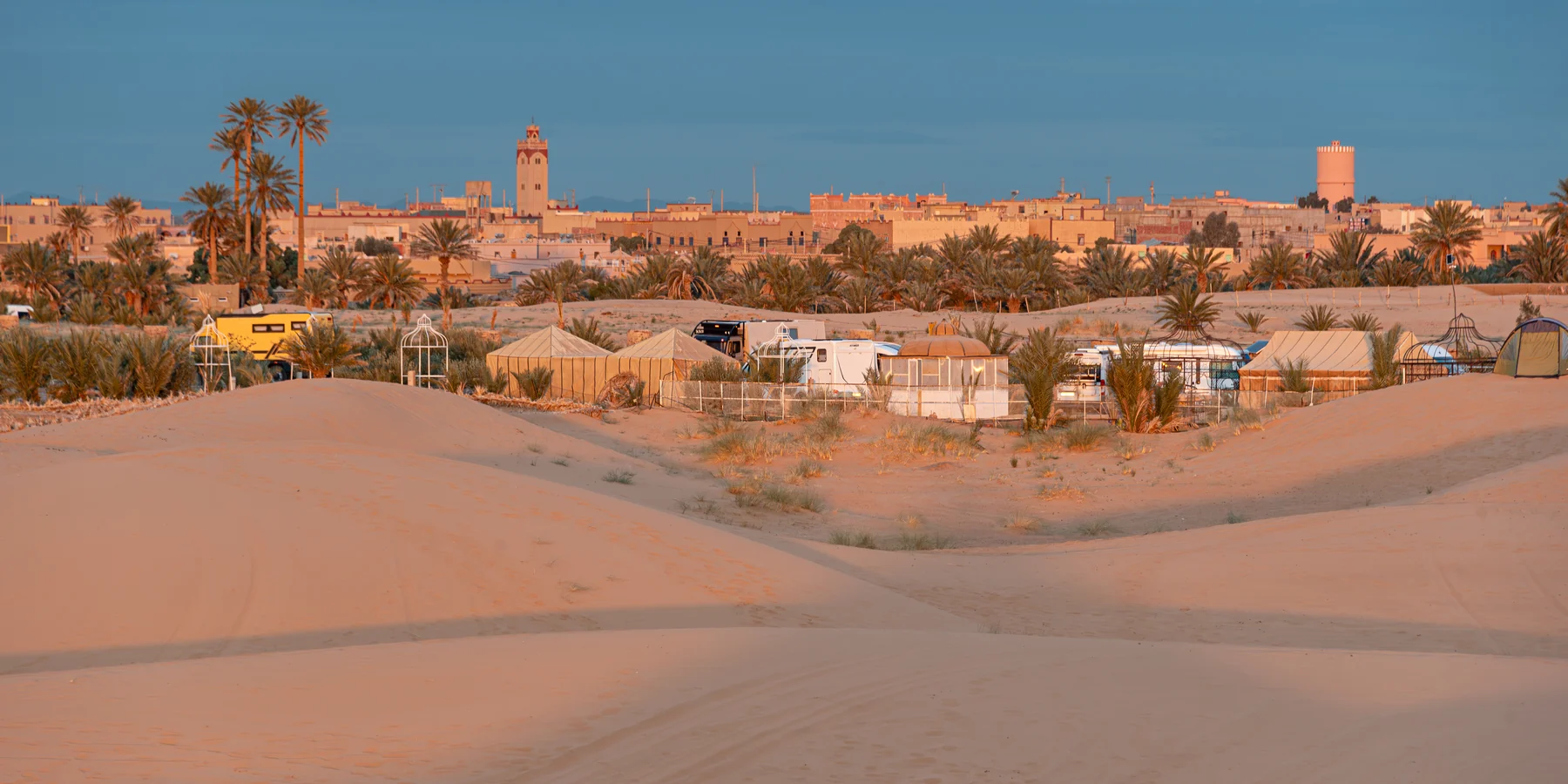 Buildings and palms in a view towards Hassilabied beside the dunes