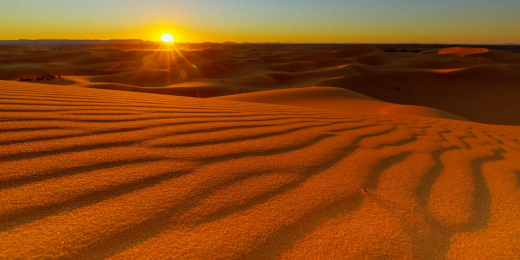 Wind-marked sand and long shadows at sunset in Erg Chebbi
